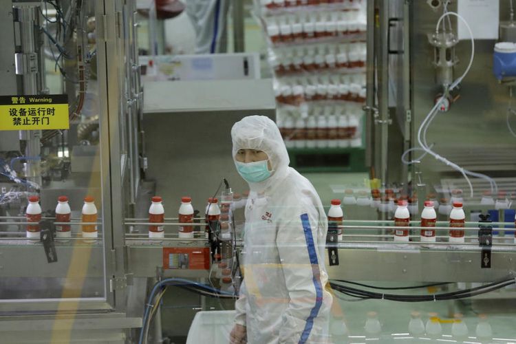 epa08252272 Workers wearing protective masks at a production line during a government-organized tour at Mengniu Dairy factory in Beijing, China, 27 February 2020. Many people returned to work in China as the Covid-19 coronavirus outbreak in the country killed over 2,700.  EPA-EFE/WU HONG