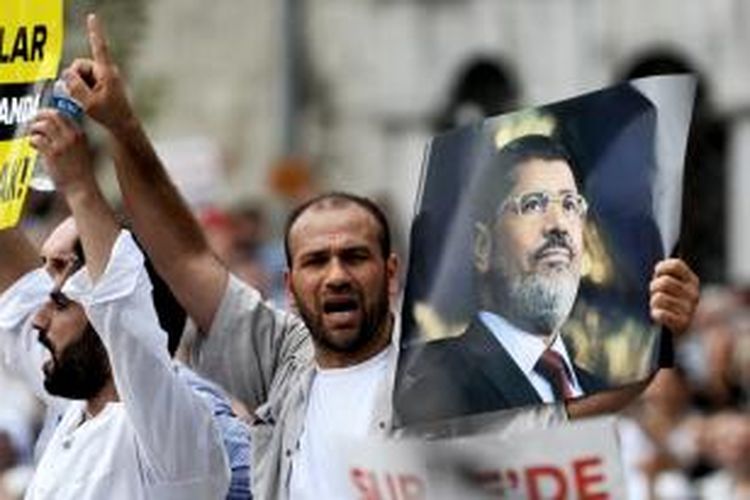 Seorang warga Turki sambil memegang foto presiden terguling Mesir, Muhammad Mursi meneriakkan dukungan untuk politisi Ikhwanul Muslimin itu. Sekitar 3.000 orang memadati jalan-jalan di Ankara, Turki dalam unjuk rasa mengecam kekerasan di Mesir.