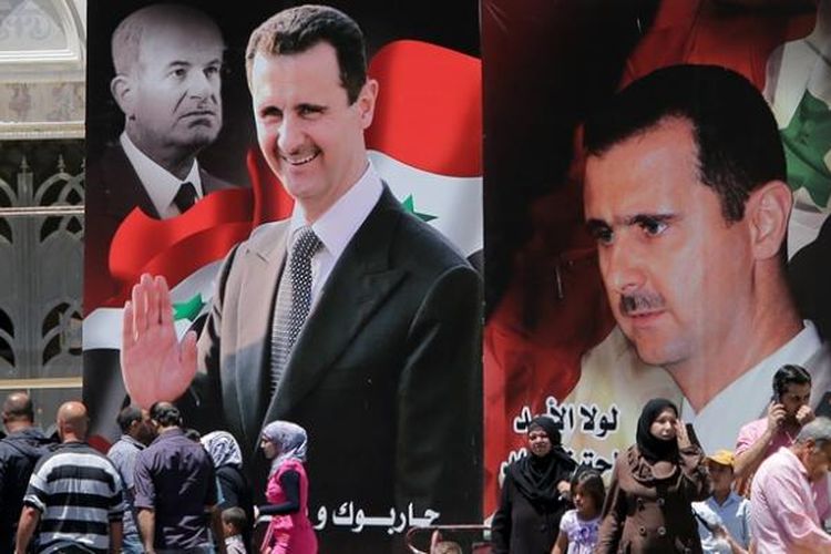 Warga Damaskus berjalan melewati poster raksasa Bashar al-Assad yang maju dalam pemilihan presiden yang digelar, Selasa (3/6/2014). 