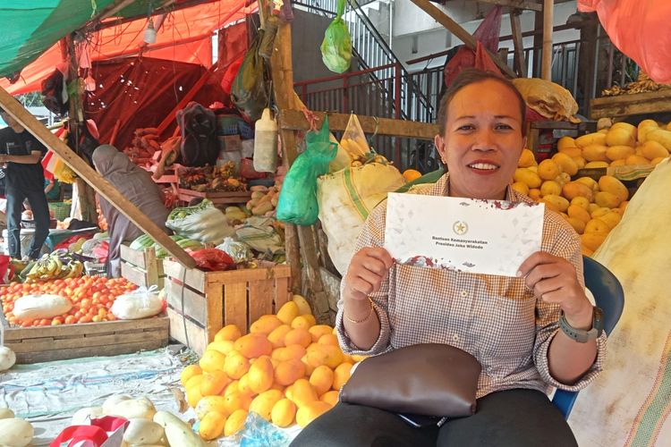 Wajah bahagia salah satu pedagang Pasar Terong Makassar yakni Ayu menunjukkan amplop bantuan pemberian Presiden Jokowi