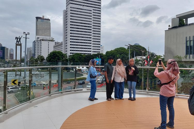 Masyarakat berfoto dengan latar Monumen Selamat Datang dari Halte Tosari, Jakarta Pusat, Rabu (28/12/2022).