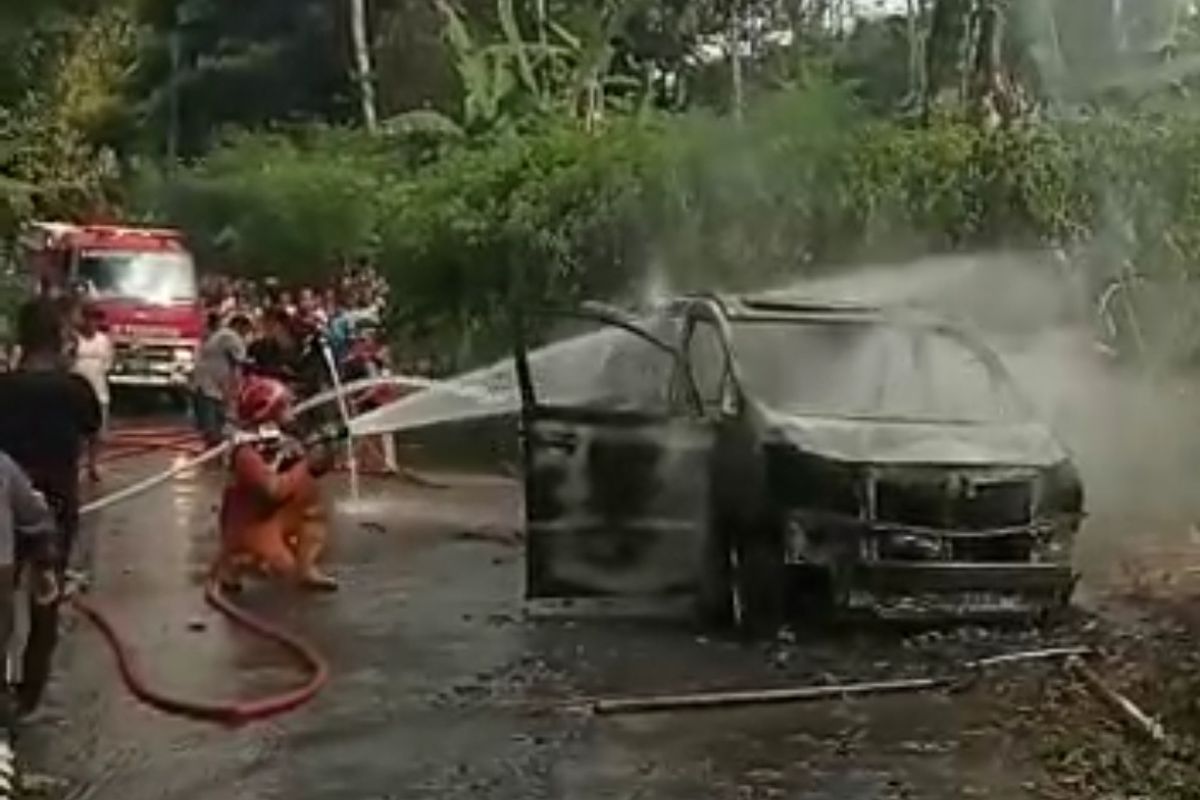 Petugas menyemprotkan air untuk memadamkan api yang membakar sebuah mobil Toyota Alphard