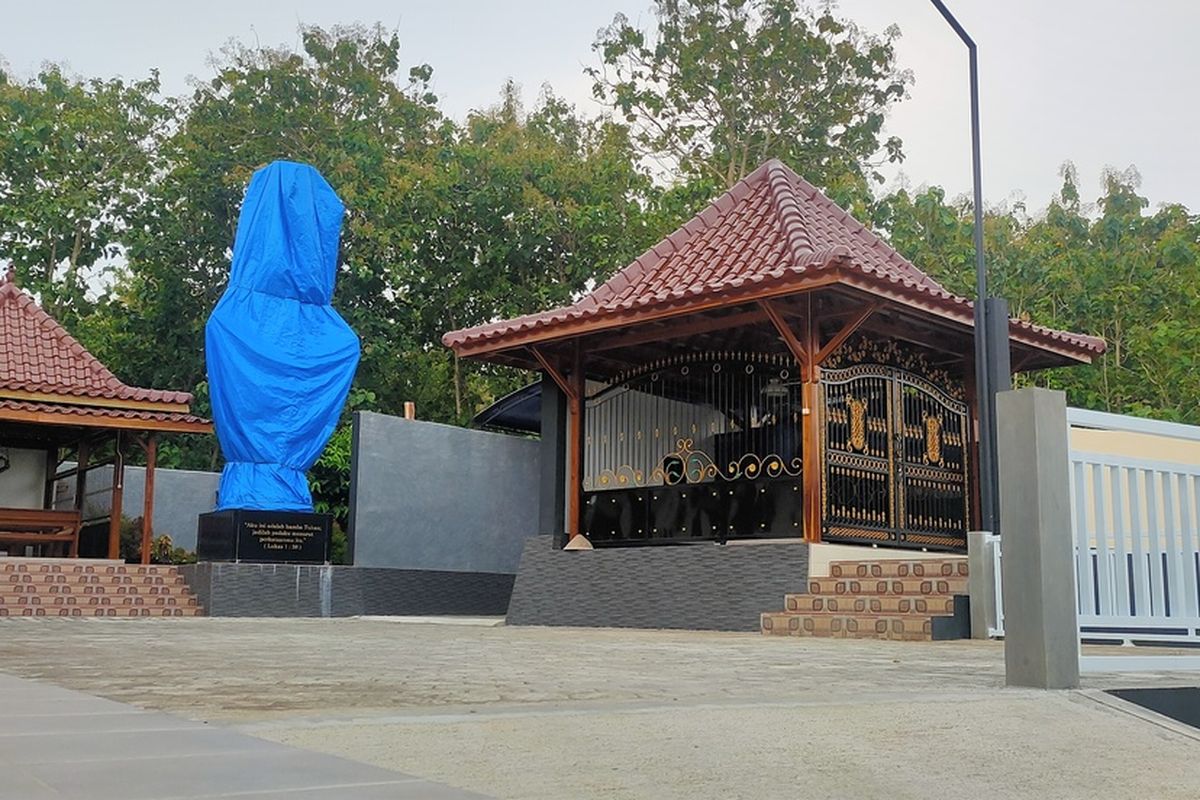 Patung Bunda Maria di Sasana Adhi Rasa “Santo Yakobus” di Pedukuhan Degolan, Kalurahan Bumirejo, Kapanewon Lendah, Kabupaten Kulon Progo, Daerah Istimewa Yogyakarta. Patung ditutup terpal biru. Tampak di samping patung itu ada cungkup besar yang disiapkan untuk suami istri pemilik komplek sasana. Istri dari pemilik komplek lebih dulu terbaring di sana.