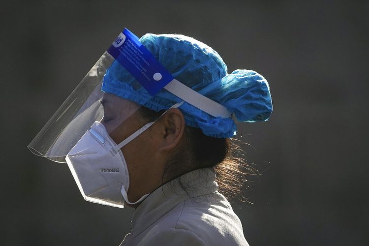 Seorang pekerja yang mengenakan pelindung wajah dan masker pelindung dari virus corona, berjalan melalui sebuah hotel yang digunakan untuk orang-orang yang bekerja di Paralimpiade Musim Dingin 2022 untuk tinggal selama masa karantina kesehatan, Sabtu (19/3/2022), di distrik Yanqing. Beijing. 