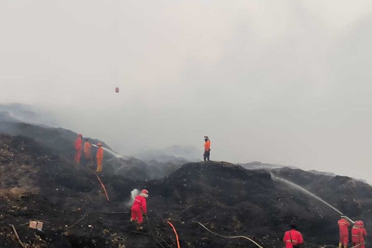 Petugas BPBD Sumatera Selatan dan tim pemadam melakukan proses pemadaman kebakaran gunung sampah di TPA Sukawinatan Palembang, Selasa (26/9/2023).