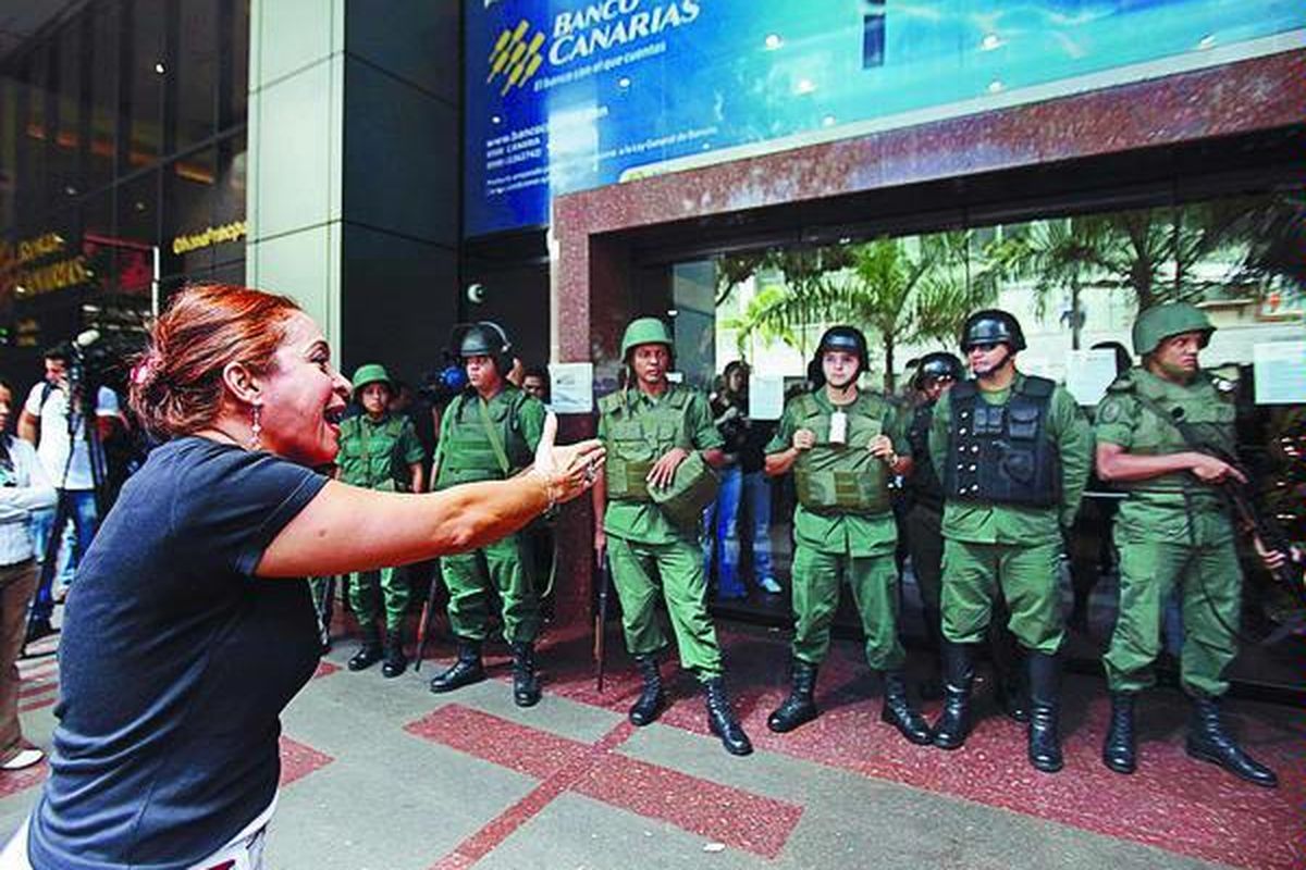 Para karyawan Banco Canarias berteriak kepada tentara karena mereka dipecat dan tak dibayar secara memuaskan dalam sebuah aksi di Caracas, Venezuela, Jumat (4/12). Pemerintah Venezuela mengambil alih pengelolaan beberapa bank kecil karena tuduhan banyaknya kesalahan dalam manajemen.