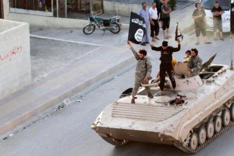 Pejuang ISIS tengah menggelar konvoi di provinsi Raqqa di atas sebuah kendaraan lapis baja.