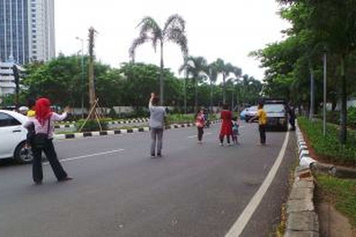 Ed (38) berbaju abu-abu dan DS (didepan) baju merah celana hitam dengan anaknya CL (4) tengah menanti pengendara yang memanfaatkan jasanya sebagai joki di SCBD, samping Polda Metro Jaya, Semanggi, Jakarta Selatan. Selasa (24/12/2013).