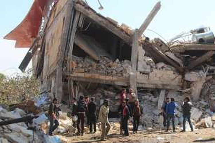 Sejumlah orang berkumpul di sekitar reruntuhan rumah sakit Doctors Without Borders dekat Maaret al-Numan, di wilayah utara Suriah. Bangunan ini menjadi sasaran serangan rudal yang menewaskan 7 orang dan menghilangkan 8 lainnya.  
