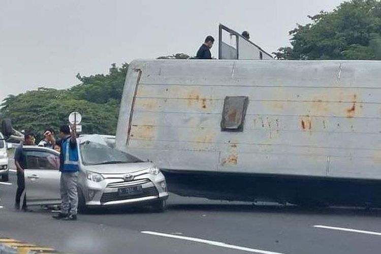 Mobil Toyota Cayla berwarna silver bernopol N-1534-BS milik pemudik tertimpa bodi bus angkutan yang terguling hingga ringsek pada kabin sisi kirinya, di Tol Surabaya-Gempol KM 756.200, Rabu (19/4/2023) siang.  