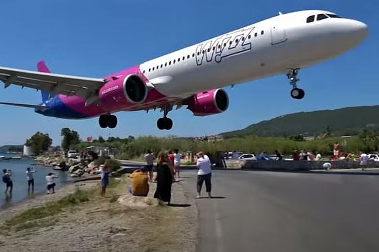 Pesawat Wizz Air terbang rendah hanya beberapa meter di atas kepala turis saat hendak mendarat di Bandara Skiathos Alexandros Papadiamantis, Jumat (5/8/2022).