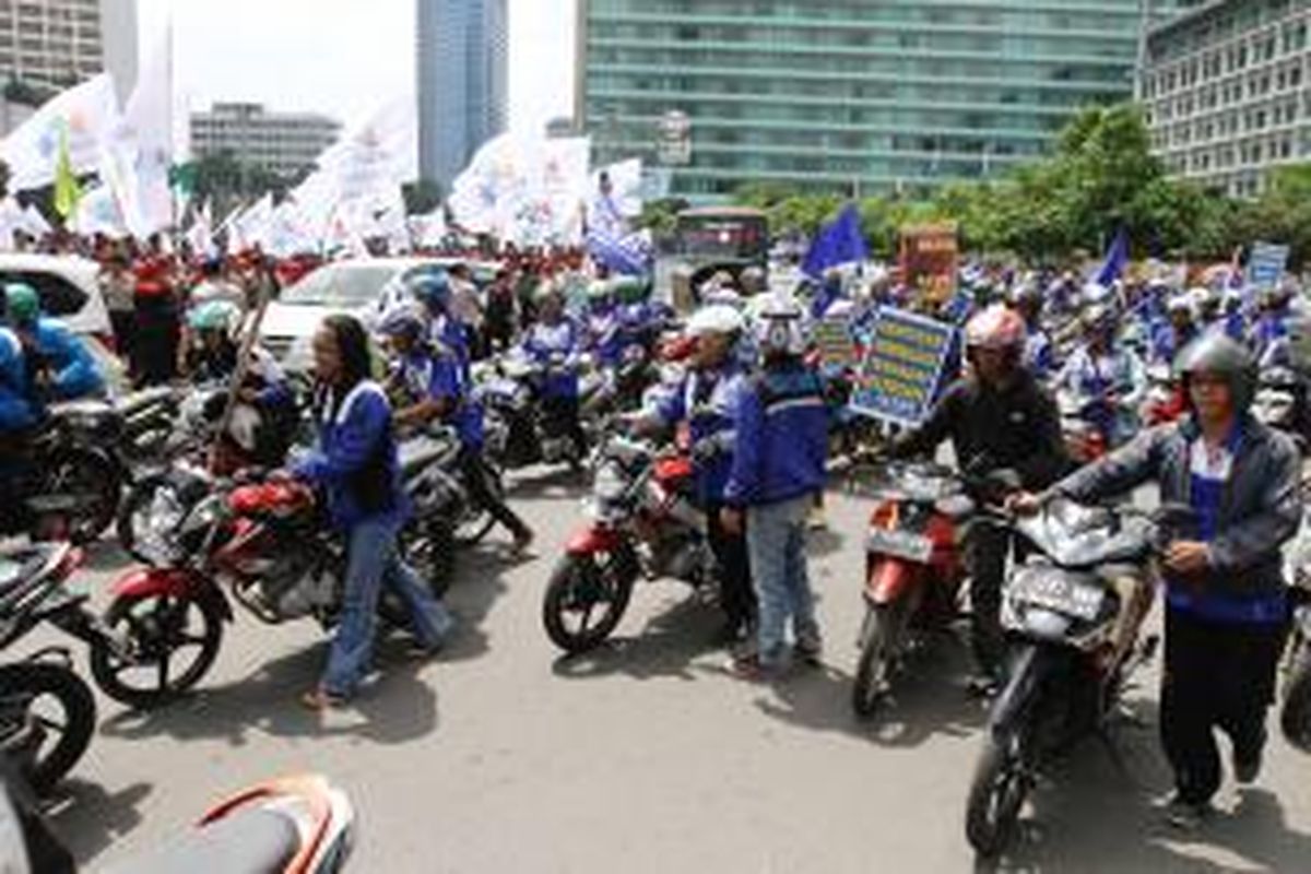 Buruh mendorong sepeda motor di kawasan Bundaran Hotel Indonesia, Jakarta Pusat, Rabu (10/12/2014), untuk memprotes kenaikan harga bahan bakar minyak (BBM).