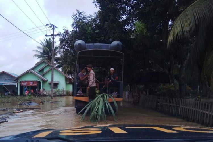 Polisi menyeberangi lokasi banjir untuk mengantarkan pengantin pria ke di Desa Ujong Baroh Beureughang, Kecamatan Tanah Luas, Aceh Utara, Kamis (4/1/2018)