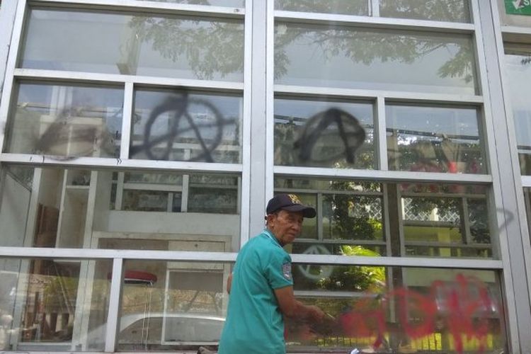 Seorang pekerja sedang membersihkan coretan di halte Jalan Surapati,  Kota Bandung, Jawa Barat.
