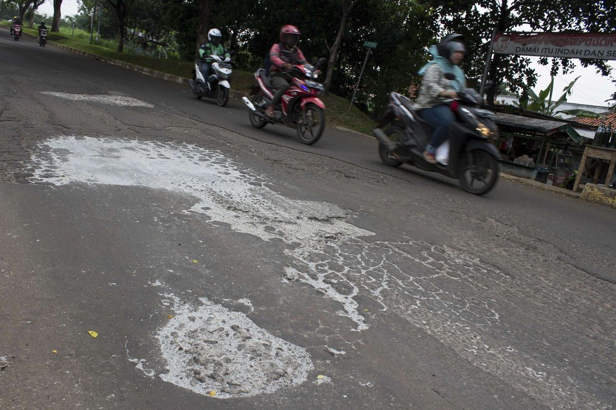 Pengendara melintasi jalan yang berlubang di Grand Depok City (GDC) Grand Depok City, Depok, Jawa Barat, Rabu, (11/12/2019). Beberapa jalan sepanjang GDC masih berlubang dan bergelombang.