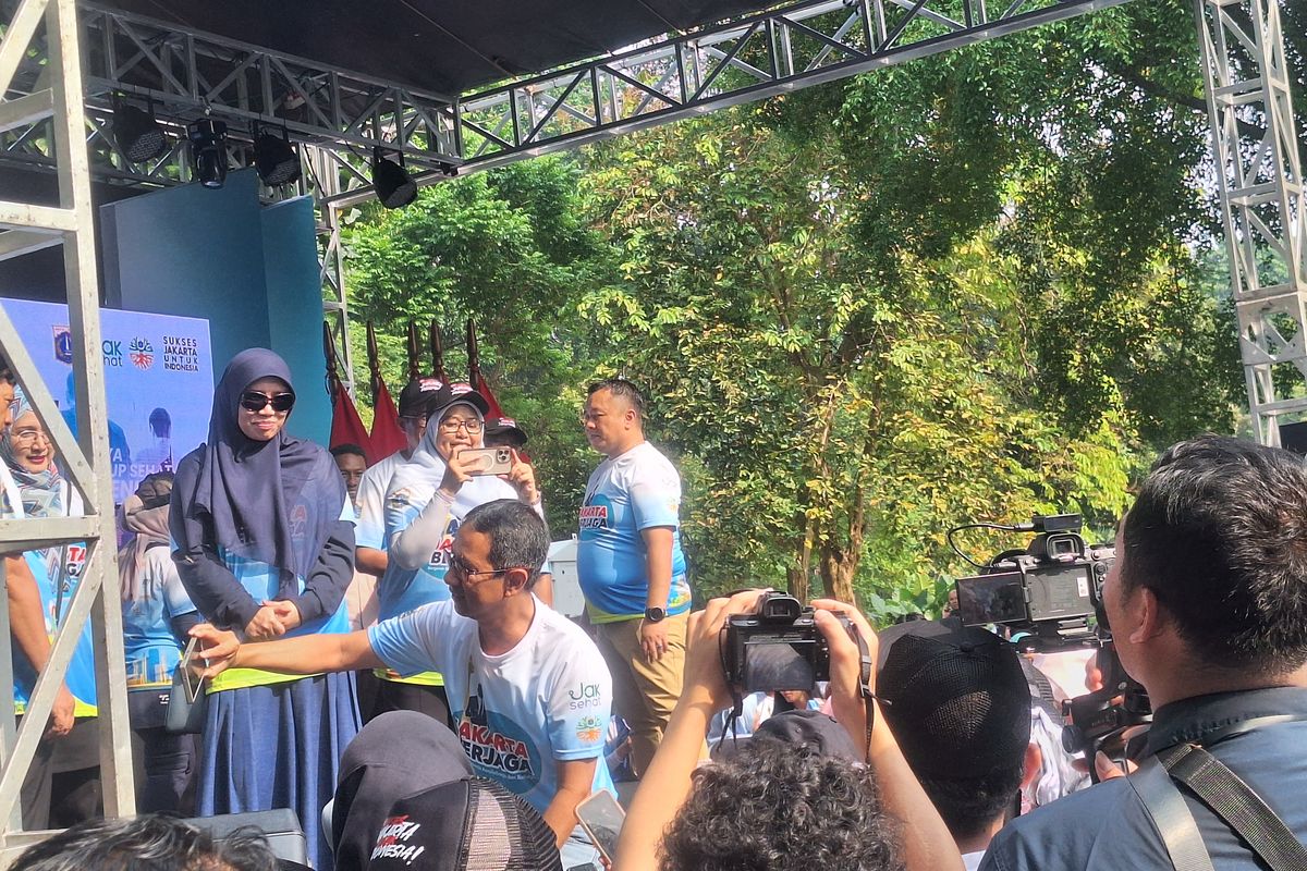 PJ Gubernur DKI Jakarta Heru Budi Hartoni melayani warga yang meminta selfie di acara puncak Jakarta Berjaga di Parkir Selatan Glora Bung Karno, Minggu (9/6/2024).