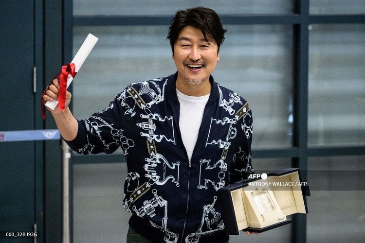 Aktor Korea Selatan Song Kang Ho memegang penghargaan sebagai aktor terbaik di Festival Film Cannes saat tiba di Bandara Internasional Incheon, pada 30 Mei 2022.