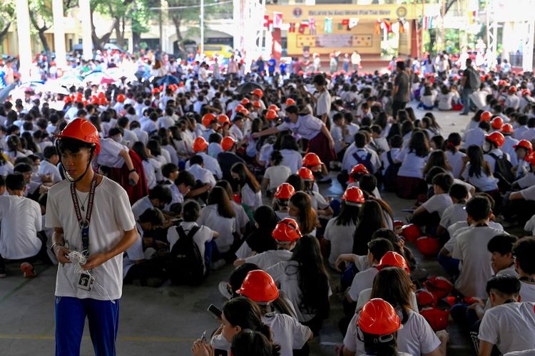 Para siswa berkumpul di luar ruangan setelah dievakuasi dari gedung sekolah mereka di Manila pada 13 Oktober 2023, setelah gempa berkekuatan Magnitudo 5,2 melanda sekitar 100 kilometer di sebelah selatan ibu kota Filipina. 