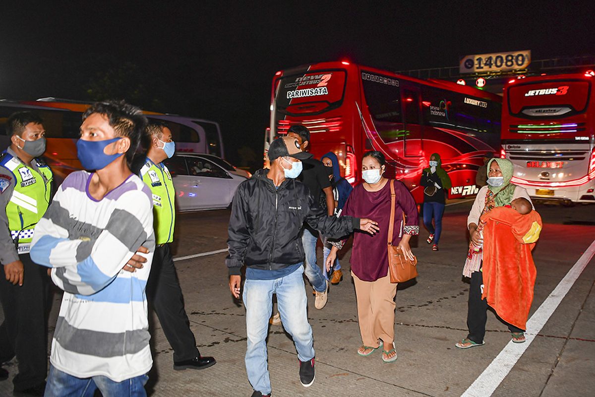 Petugas kepolisian mengarahkan calon pemudik yang terjaring razia penyekatan di Pintu Tol Cikarang Barat, Bekasi, Jawa Barat, untuk menaiki bus yang akan membawa mereka ke Terminal Pulo Gebang, Jakarta, , Kamis (21/5/2020). Calon pemudik yang terjaring razia penyekatan oleh Polda Metro Jaya tersebut dibawa ke Terminal Pulo Gebang untuk kemudian diarahkan kembali menuju Jakarta.