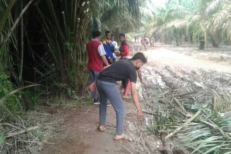 Para pelajar SMA Negeri 1 Pulau Rimau, Kabupaten Banyuasin Gotong royong memperbaiki jalan rusak yang berlumpur akibat terkena hujan lebat.