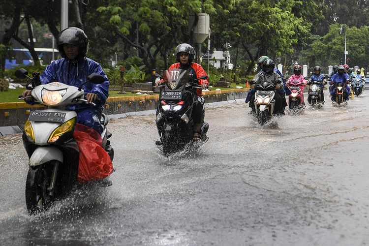 Pengendara sepeda motor melintasi banjir di Jalan Medan Merdeka Barat, Jakarta, Minggu (2/2/2020). Hujan deras yang mengguyur Jakarta pada Minggu (2/2) pagi menyebabkan beberapa ruas jalan di ibu kota tergenang banjir dengan ketinggian 10-50 centimeter.