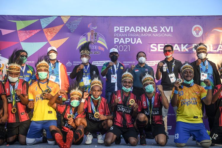 Menteri Pemuda dan Olahraga Zainudin Amali (ketiga kanan) berfoto bersama tim sepak bola CP Papua usai partai final sepak bola CP Peparnas Papua antara tim Papua melawan tim Kalimantan Selatan di Stadion Mahacandra Universitas Cendrawasih, Jayapura, Papua, Jumat (12/11/2021). Kalimantan Selatan memilih untuk tidak melanjutkan pertandingan di babak kedua sehingga pertandingan dimenangkan oleh Papua dengan skor 5-1. ANTARA FOTO/Raisan Al Farisi/nym.