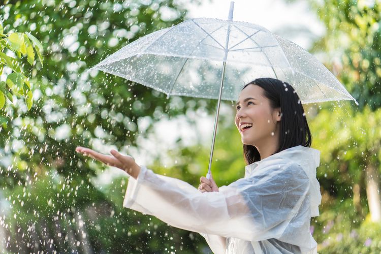 Ilustrasi perempuan memakai payung saat hujan.