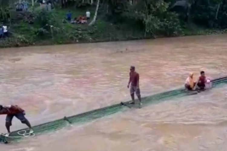 Petugas Kodim 0612 Tasikmalaya dan Polres Tasikmalaya bersama warga membantu penyeberangan darurat memakai rakit di sungai pasca-ambruknya jembatan permanen akibat banjir bandang, Selasa (23/6/2020).