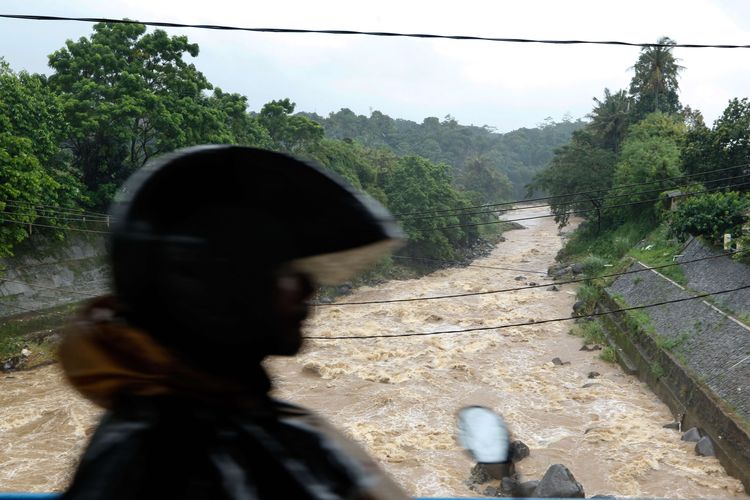 Warga melintasi Bendungan Katulampa, Bogor, Senin (24/2/2020). Level ketinggian air di Bendung Katulampa mencapai 70 cm atau siaga 4.