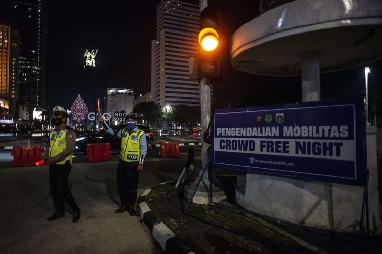 Polisi Lalu Lintas dan petugas Transjakarta berjaga saat berlangsungnya Crowd Free Night  di kawasan Bundaran HI, Jakarta, Jumat (31/12/2021). Polda Metro Jaya memberlakukan pengendalian mobilitas Crowd Free Night (malam bebas keramaian) pada malam tahun baru 2022 yang berlangsung mulai pukul 22.00 - 04.00 WIB.