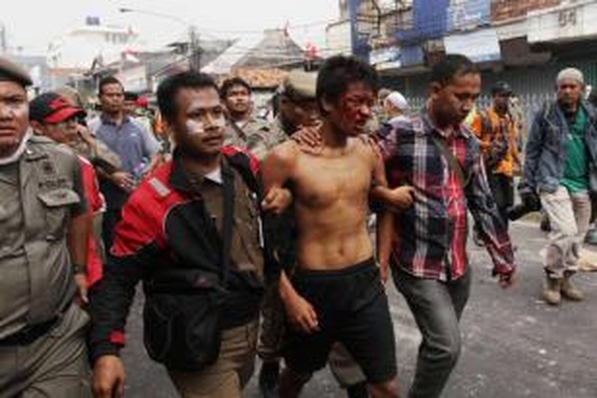 Seorang warga Kampung Pulo, Jakarta Timur, tertangkap saat terlibat kerusuhan dengan Satpol PP dan polisi di Jalan Jatinegara Barat, Kamis (20/8/2015). Kerusuhan terjadi karena warga menolak digusur dan dipindahkan untuk normalisasi Kali Ciliwung.