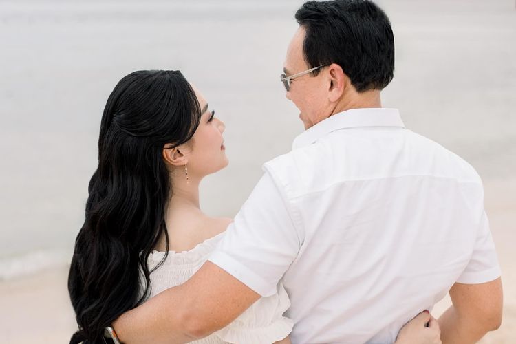 Puput Nastiti Devi tampil anggun dengan long dress putih, makeup natural, dan rambut wavy saat foto kehamilan anak ketiga bersama keluarga.