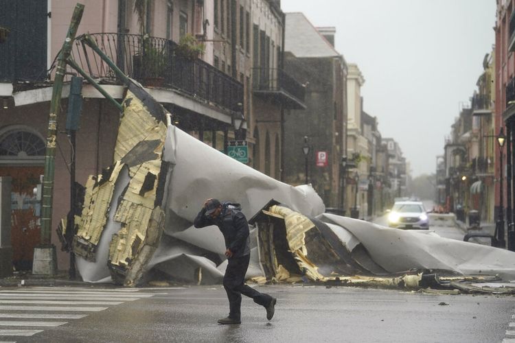 Seorang pria melewati bagian atap yang roboh akibat tertiup Badai Ida dari sebuah bangunan di French Quarter, New Orleans, AS, pada Minggu (29/8/2021).
