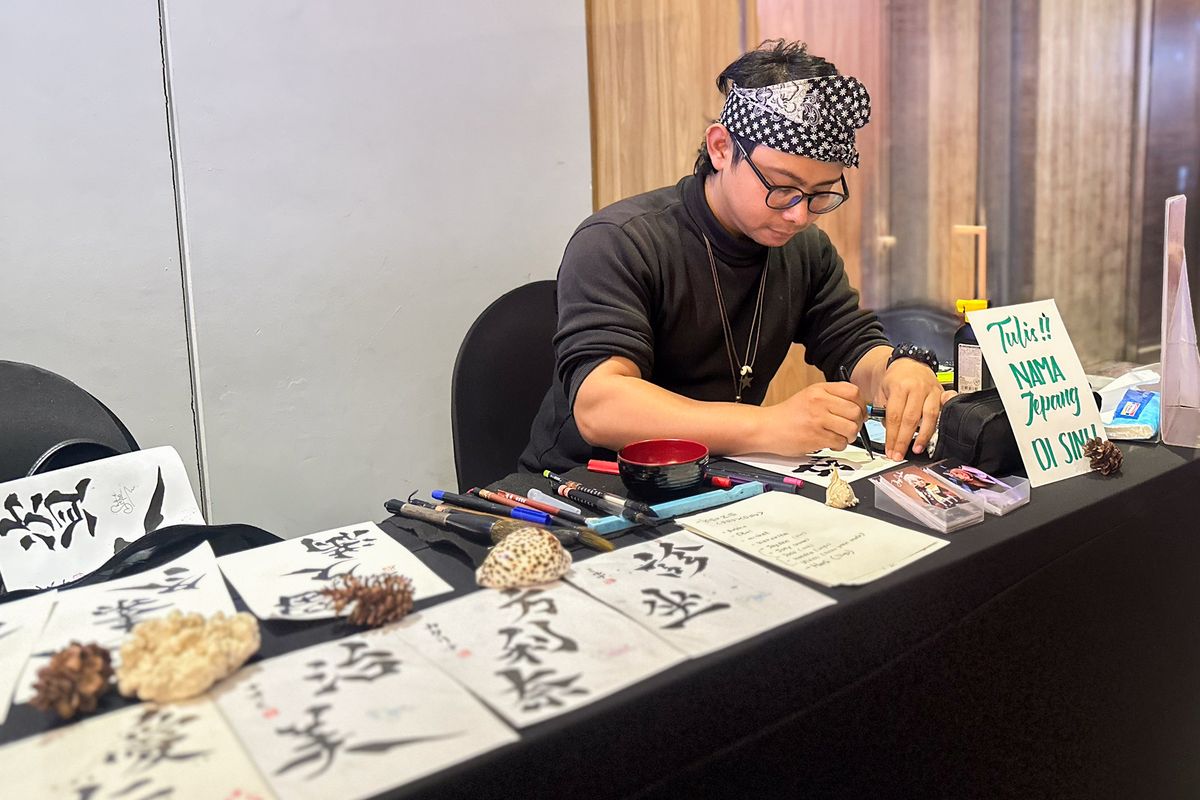 Seniman Shod&otilde; sedang menuliskan aksara nama Jepang di Archipelago Japanese Street Food Festival.