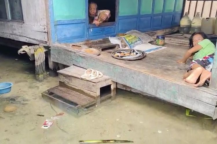 Dua orang warga di desa Saobi yang beetahan di rumah akibat banjir rob. 