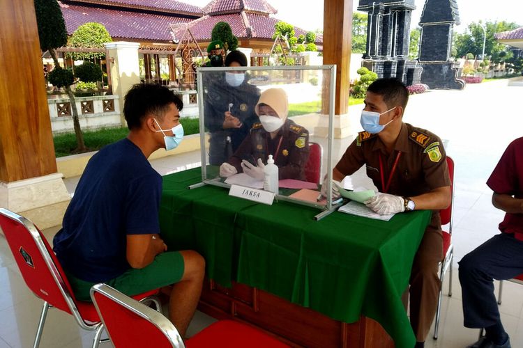 Seorang pelanggar protokol kesehatan membayar denda di meja Kejaksaan Negeri Blitar setelah mendapatkan putusan hukuman denda pada sidang yang digelar di halaman Pemerintah Kabupaten Blitar selama operasi yustisi di Jalan Raya Kanigoro-Blitar, Rabu (7/7/2021)