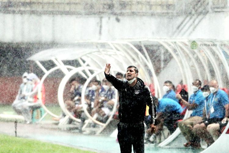 Diguyur hujan deras pelatih baru Persipura Jayapura Angel Alfredo Vera memberi intruksi kepada pemain pada pertandingan melawan Persikabo 1973 pada pekan ke-13 Liga 1 2021-2022 yang berakhir dengan skor 2-1 di Stadion Maguwoharjo Sleman, Senin (22/11/2021) sore.