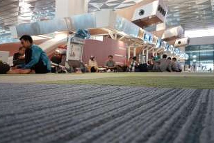 Sejumlah penumpang terpaksa duduk di karpet dekat area check in Terminal 3 New Bandara Soekarno-Hatta, Tangerang, Selasa (9/8/2016). Pada hari pertama operasional Terminal 3 New, penumpang mengeluhkan jumlah tempat duduk yang terbatas.