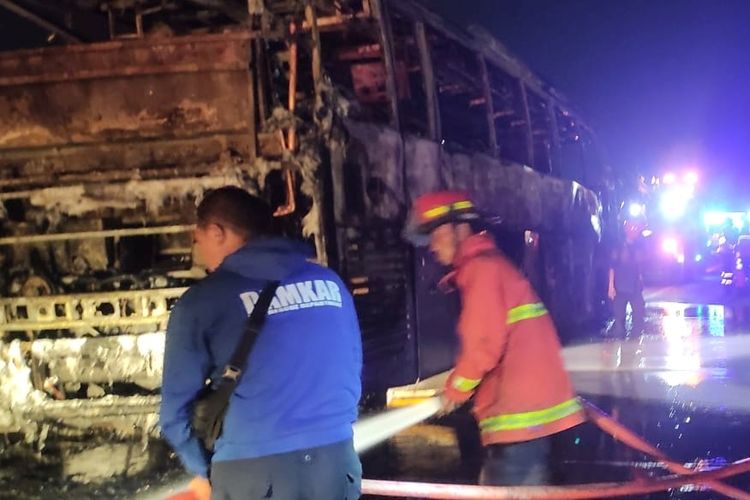 Petugas Damkar menyemprot air ke badan bus pariwisata yang terbakar di ruas tol Pejagan - Pemalang KM 259 sekitar pukul 23.00 WIB, Selasa (4/7/2023). (Dok. Damkar Brebes)