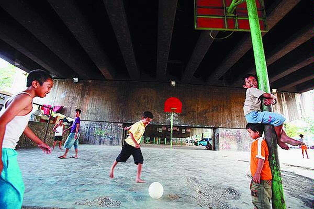 Anak-anak bermain bola di lapangan dengan memanfaatkan lahan di bawah kolong tol Jembatan Tomang, kawasan Jati Pulo, Jakarta, Senin (28/7). Lahan di bawah kolong tol apabila diolah dapat menjadi ruang publik yang bermanfaat.