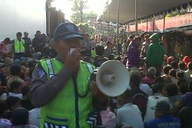 Seorang petugas keamanan mengatur antrean warga di lingkungan PT Gudang Garam, Kota Kediri, Jawa Timur, Selasa (6/8/2013). Ribuan warga mengantre untuk mendapatkan 