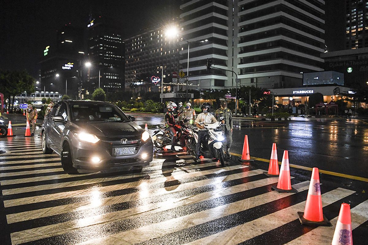 Petugas kepolisian dan Satpol PP meminta pengendara memutar arah saat diberlakukannya Car Free Night (malam bebas kendaraan)  dan Crowd Free Night (malam bebas keramaian) pada malam pergantian tahun di Jalan MH Thamrin, Jakarta (31/12/2020). Polda Metro Jaya melakukan Car Free Night dan Crowd Free Night dengan menutup sepanjang Jalan Sudirman-MH Thamrin, Jakarta pada malam pergantian tahun untuk mencegah kerumunan warga.