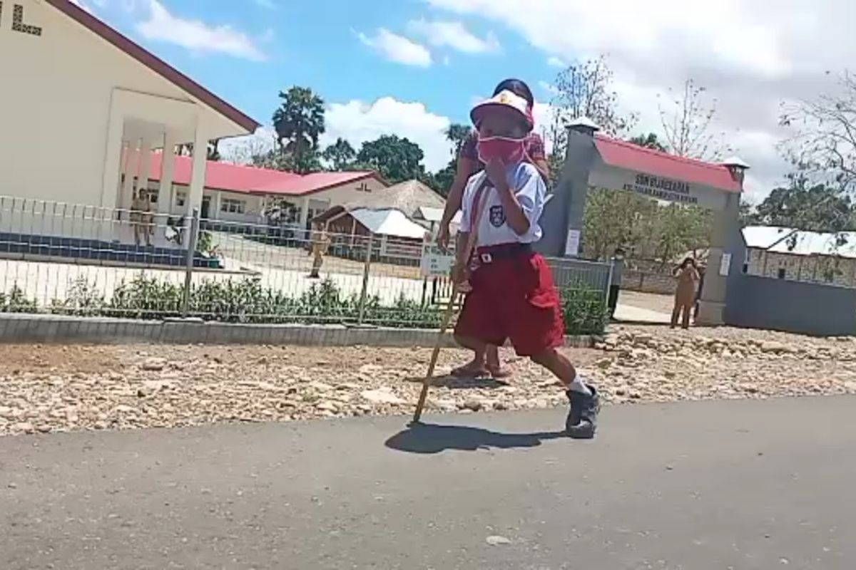 Stenly Yesi Ndun, bocah berusia tujuh tahun yang memiliki satu kaki, saat memakai tongkat untuk ke sekolah