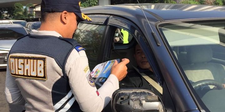 Petugas melakukan sosialisasi uji coba ganjil genap untuk lalu lintas Asian Games 2018 di Jalan Tomang Raya pada Senin (2/7/2018).