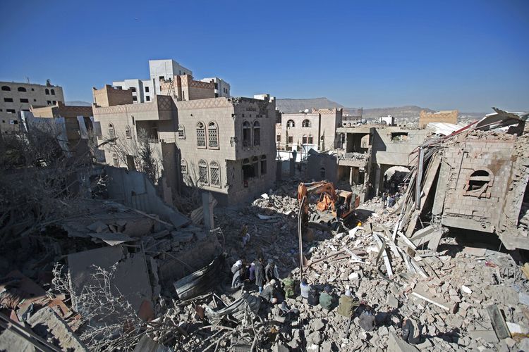 Orang-orang memeriksa puing-puing bangunan yang rusak akibat serangan udara koalisi pimpinan Saudi, di Sanaa, Yaman, Selasa, 18 Januari 2022. 