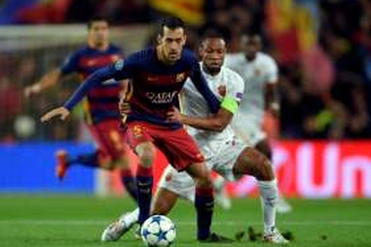 Gelandang Barcelona, Sergio Busquets, dikawal oleh pemain AS Roma, Seydou Keita, pada partai fase grup Liga Champions di Stadion Camp Nou, 24 November 2015.