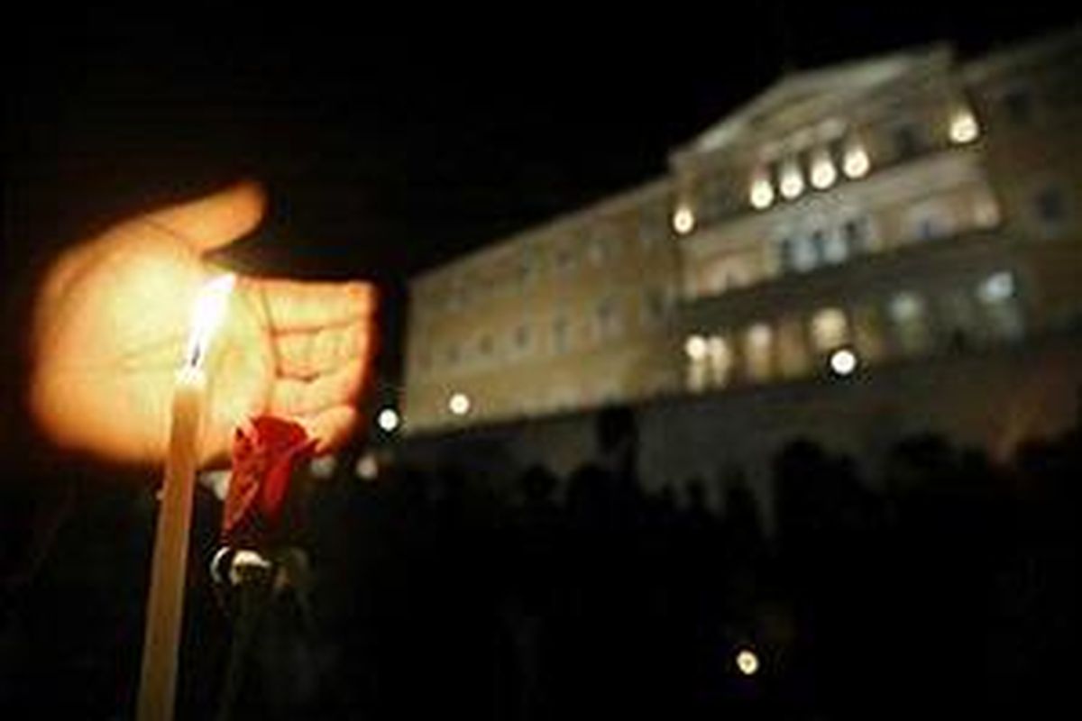 Seorang demonstran menggenggam sebuah lilin dan sepucuk mawar merah di depan Gedung Parlemen Yunani dalam sebuah unjuk rasa di Athena, 13 Desember 2008.
