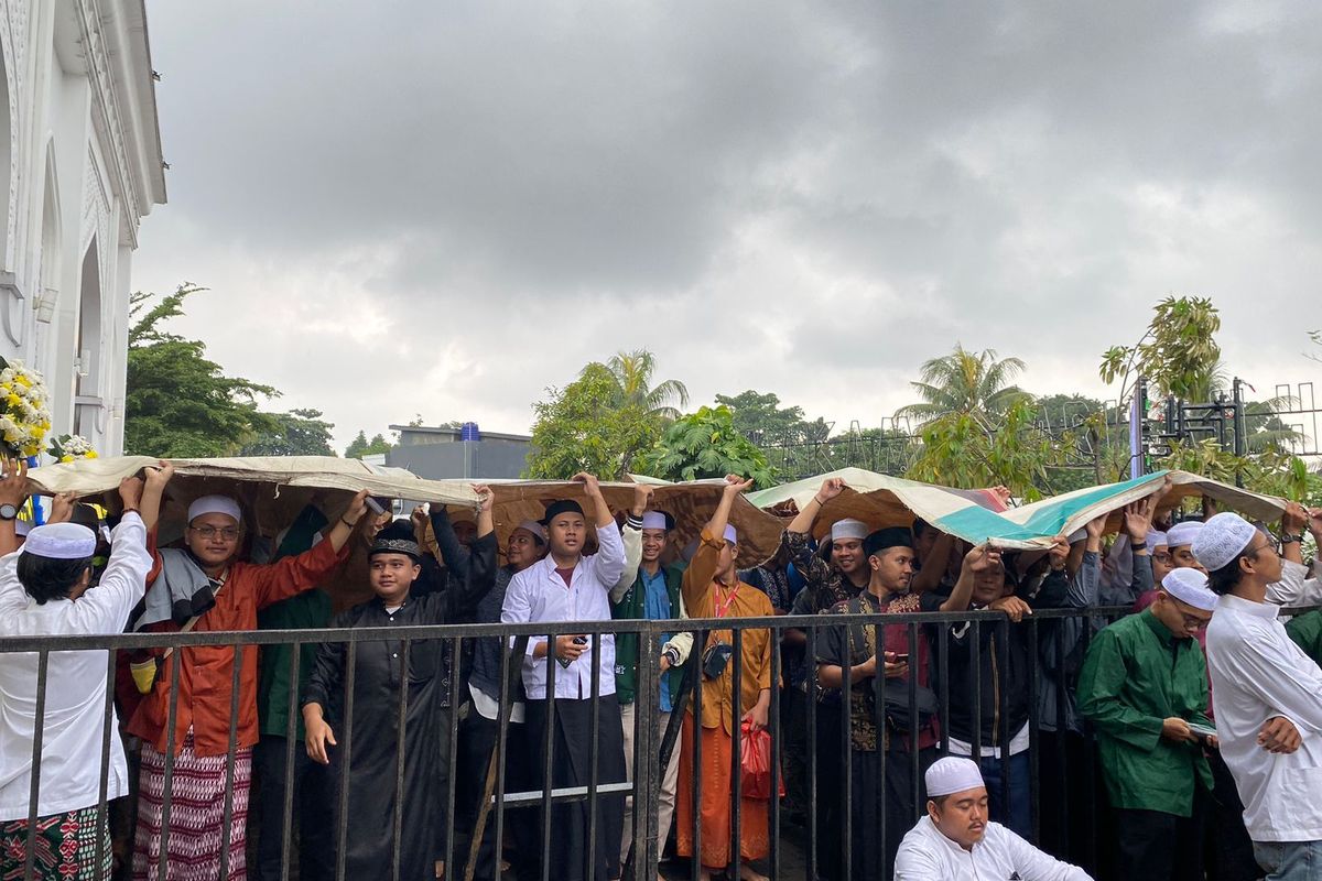 Para pelayat Habib Hasan bin Ja'far Assegaf yang berlindung dari hujan menggunakan alas terpal di luar Masjid Nurul Musthofa Center, Cilodong, Depok, Kamis (14/3/2024).