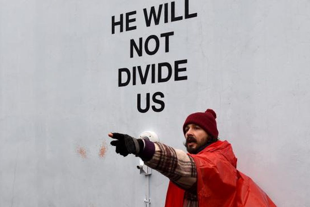 Aktor Shia LaBeouf (bertopi merah) melakukan unjuk rasa menentang Donald Trump di Museum of the Moving Image di Astoria, Queens, New York, AS, pada Selasa (24/1/2017).