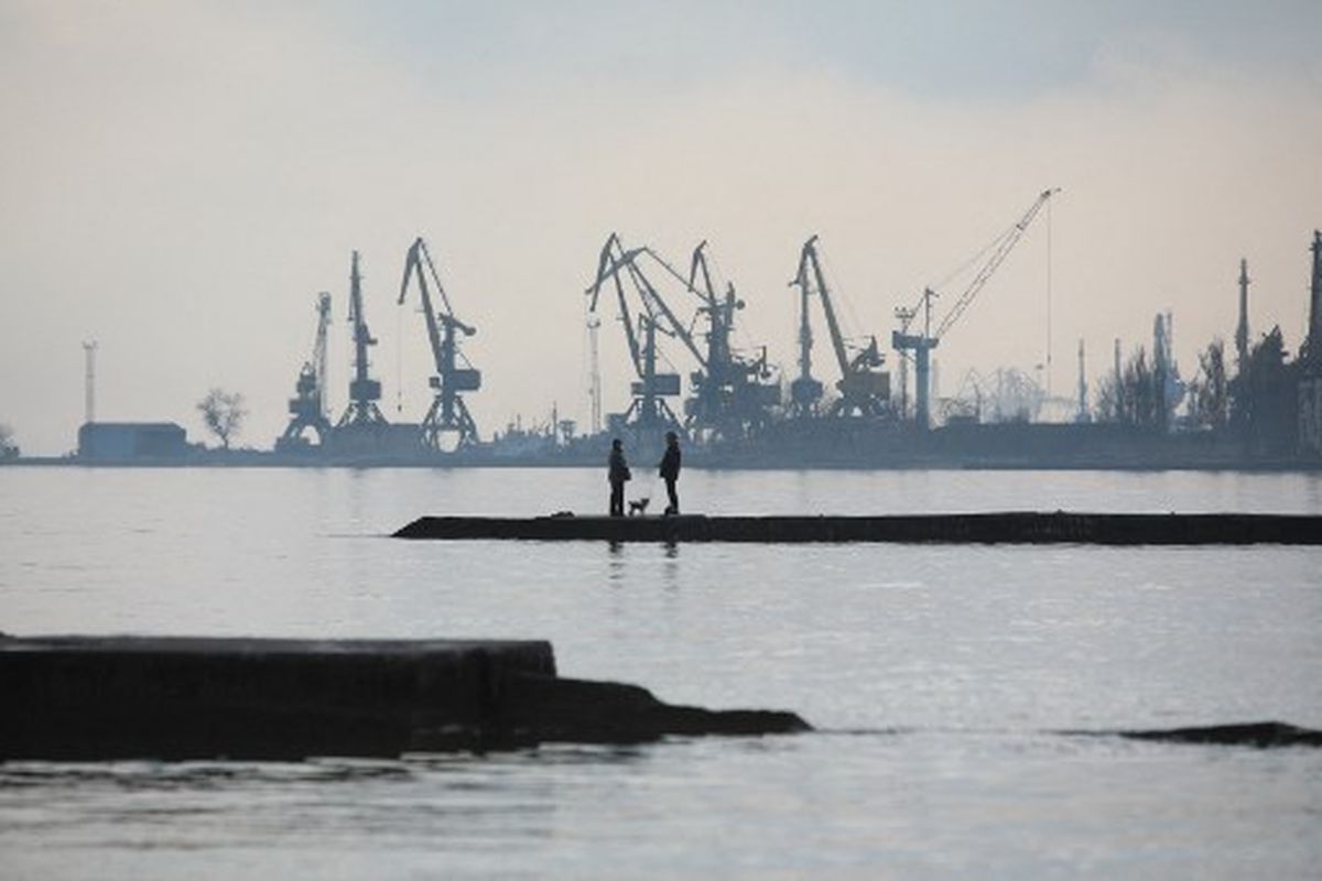 Pasangan berjalan dengan seekor anjing di dermaga di pantai Laut Azov di kota pelabuhan industri Mariupol, Ukraina pada Rabu (23/2/2022). Mariupol terletak di tepi garis depan yang memisahkan wilayah yang dikendalikan pemerintah dari yang diawasi oleh Rusia- mendukung separatis di kubu pemberontak Donetsk.